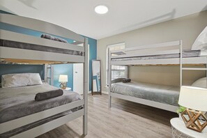 A room with bunk beds, a bedside table with a lamp, and a window with blinds. - Best of Allen at Fountain Park 5-bd/2-ba w/ Pool (Allen)