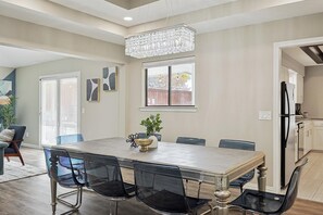 A dining area with a large table, chairs, a chandelier, and a view of the outside. - Best of Allen at Fountain Park 5-bd/2-ba w/ Pool (Allen)
