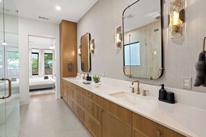 A modern bathroom with a large mirror, dual sinks, and wooden cabinetry. - 6bd/5ba of Modern Elegance Cinema, Games, Hottub (Dallas)