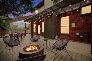 An outdoor patio with a fire pit, wicker chairs, and string lights. - Live Like Royalty - Highland Village 6BR Mansion (Lewisville)