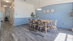 Ein Essbereich mit Holztisch und Stühlen, einer hängenden Leuchte und gerahmten Bildern an der Wand.