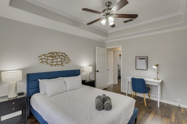 A bedroom with a bed, a desk, a chair, a ceiling fan, and a wall decoration. - Spacious and Luxury Home w/ Cinema Room and Pool (Grand Prairie)