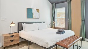 A bedroom with a bed, bedside tables, a bench, a painting, and curtains. - Paradise, Modern Home, Pool & Hot Tub (Waxahachie)