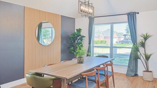 A dining area with a wooden table, chairs, a mirror, and potted plants. - Paradise, Modern Home, Pool & Hot Tub (Waxahachie)