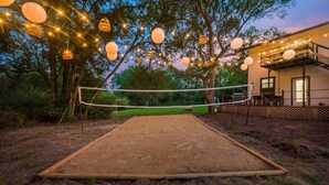 A volleyball court with a net, surrounded by trees and string lights. - Tropical Oasis - Pool + Beach Volleyball + Firepit (Lancaster)