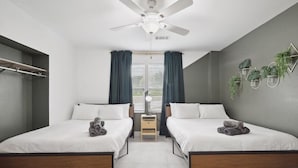 A modern bedroom with two beds, a ceiling fan, and a small table between the beds. - Tropical Oasis - Pool + Beach Volleyball + Firepit (Lancaster)