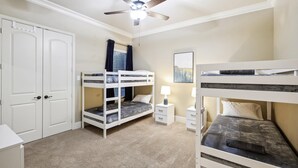 A bunk bed room with a ceiling fan, white wardrobe, and a painting on the wall. - Lakefront Mansion With Pool and Cinema (Wylie)
