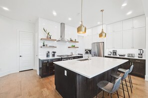 A modern kitchen with a large island, dark cabinetry, white subway tiles, and pendant lighting. - Best of The Cedars - Dallas Views, Rooftop Luxury (Dallas)