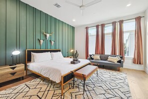 A bedroom with a bed, bedside tables, a bench, a cactus, and a wall-mounted bull skull. - Best of The Cedars - Dallas Views, Rooftop Luxury (Dallas)