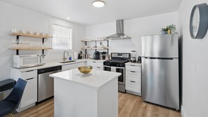 Una cocina moderna con armarios blancos, electrodomésticos de acero inoxidable y una isla central.