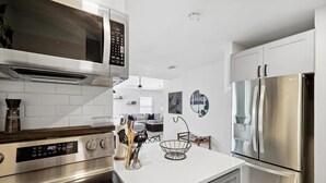 A modern kitchen with stainless steel appliances, white cabinetry, and a clean, minimalist design. - Cozy & Modern Home in Heart of Dallas (Dallas)
