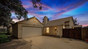 A two-story house with a garage, a front door, and a wooden fence. - Cozy & Modern Home in Heart of Dallas (Dallas)