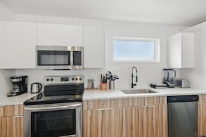A modern kitchen with white cabinets, stainless steel appliances, and a window above the sink. - Heart of Dallas in Knox Henderson Sleeps 4 (Dallas)