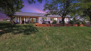 A house with a covered patio, outdoor seating, and a lawn. - Lone Star Getaway - 5bd/3ba w Game Room & Backyard (McKinney)