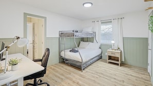 A bunk bed with a desk and chair, a bedside table with a lamp, and a window with curtains. - Lone Star Getaway - 5bd/3ba w Game Room & Backyard (McKinney)