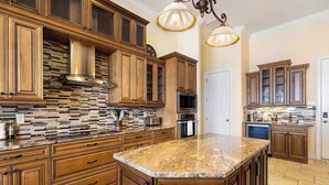 A spacious kitchen with wooden cabinets, a granite countertop, and a built-in stove. - Peace River Waterfront Luxury Living - 5-bd w Pool (Punta Gorda)