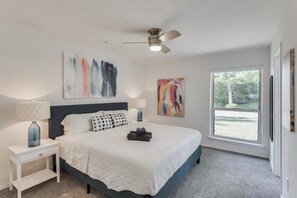 Ein Schlafzimmer mit einem Bett, einem Nachttisch, einem Deckenventilator und Kunstwerken an den Wänden.