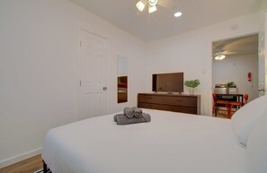 Ein Schlafzimmer mit Bett, Kommode, Spiegel und Schreibtisch mit Stuhl.
