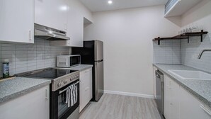 A compact kitchen with white cabinets, a microwave, a refrigerator, an oven, and a dishwasher. - Greater Uptown 1bd, 1BA Apt, Mins to Attractions (Houston)