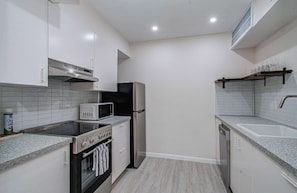 A compact kitchen with white cabinets, a microwave, a refrigerator, an oven, and a dishwasher. - Greater Uptown 1bd, 1BA Apt, Mins to Attractions (Houston)