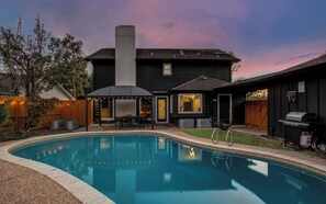 A backyard with a swimming pool, a covered patio, and a barbecue area. - 5BD Cozy Rustic Retreat - Pool & Firepit (Houston)