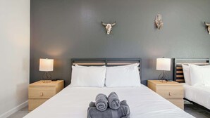 Habitación de hotel con una cama grande, dos mesitas de noche con lámparas, cabecero y calaveras decorativas en la pared.