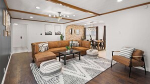 Een moderne woonkamer met een bruine leren bank, een bijzettafeltje en een vloerkleed met dessin.