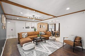 Ein modernes Wohnzimmer mit einem braunen Ledersofa, einem Couchtisch und einem gemusterten Teppich.