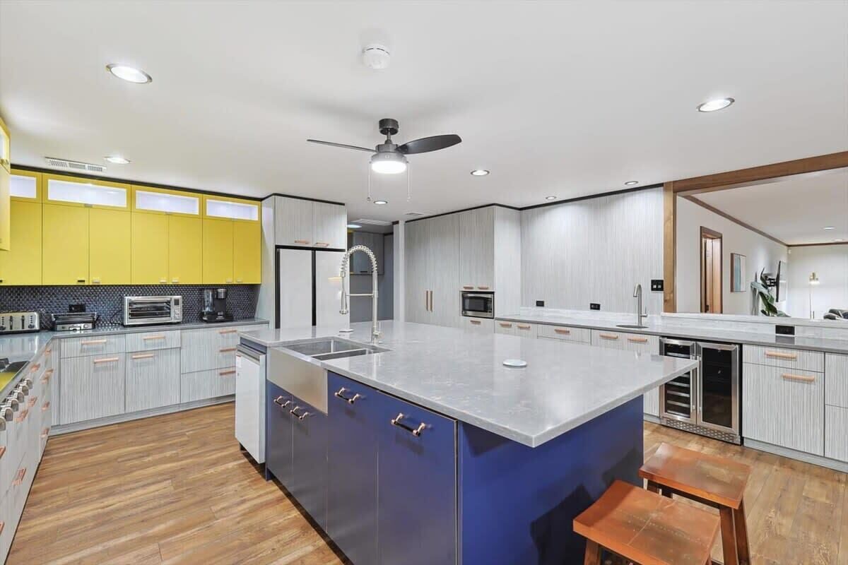 A modern kitchen with a large island, built-in appliances, and a ceiling fan.