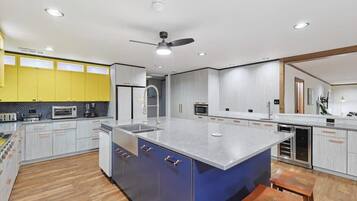 A modern kitchen with a large island, built-in appliances, and a ceiling fan.