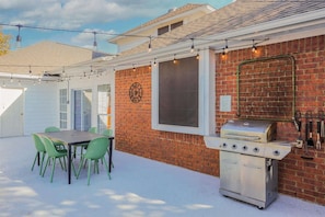 Eine Terrasse mit Grill, Tisch und Stühlen im Freien.