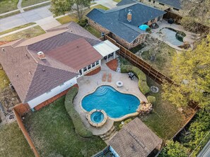 Ein Wohnhaus mit Swimmingpool, überdachter Terrasse und umzäunter Garten.