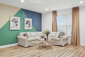 A living room with a sectional sofa, a round coffee table, and two abstract paintings on the wall. - 2-bd/2-ba Apartment w Pool & Patio (Dallas)