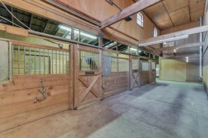A stable with wooden stalls, metal gates, and a concrete floor. - Spacious Ranch Style Home w/ Cinema Room (Celina)