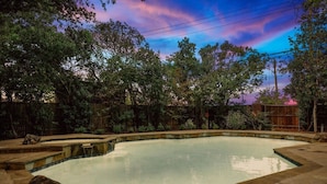 An outdoor swimming pool with a stone border, surrounded by trees and a wooden fence. - Tropical Pool Oasis - 5 BR, Foosbal, Cinema (Flower Mound)