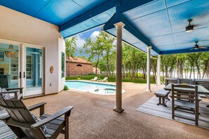 Ein überdachter Außenbereich mit Pool, Sitzgelegenheiten und einem Backsteingebäude im Hintergrund.