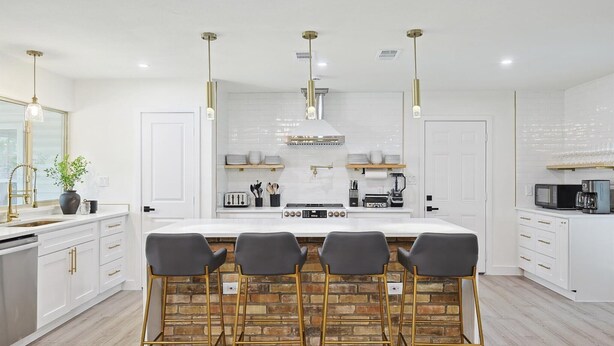A modern kitchen with white cabinetry, a central island with bar stools, and pendant lighting. - 3-bd Backyard Oasis w Pool, Patio, Firepit (Irving)