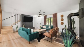 A modern living room with a sofa, chairs, a TV, and a cactus. - Tranquil Country Escape, 4 Bedrooms, Pond, Firepit (Greenville)
