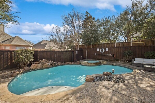 Ein Garten mit Swimmingpool, Holzzaun und Steinmauerung.