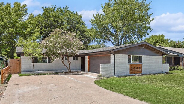 A single-story house with a garage, a small front yard, and a wooden fence. - Bright Modern Home 3br, 2ba, Fenced backyard (Irving)
