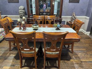 Ein Esszimmer mit Holztisch und -stühlen, einem Ziertepiegel und einer Statue.