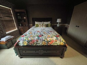 A bedroom with a large bed, a nightstand, a dresser, and a window with blinds. - 5BD DFW Mansion - Pool, Cinema, Games (Plano)