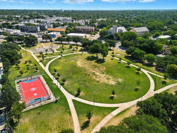 An aerial view of a residential area with a large green park, a basketball court, and surrounding houses. - Centrally Located Cheerful 1bd/1ba Apt (Dallas)