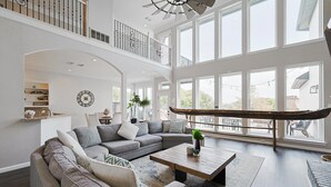 Ein geräumiges Wohnzimmer mit einer großen Eckcouch, einem Couchtisch und Blick ins Freie durch große Fenster.