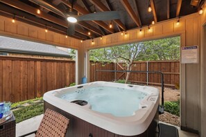 Un bain à remous avec une terrasse en bois, un patio couvert et un panneau indiquant les règles de sécurité.