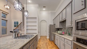 A modern kitchen with a central island, stainless steel appliances, and a wooden floor. - High End In The Center - Mins to Downtown w Pool (Houston)