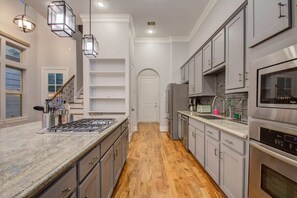 A modern kitchen with a central island, stainless steel appliances, and a wooden floor. - High End In The Center - Mins to Downtown w Pool (Houston)