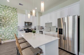A modern kitchen with white cabinets, stainless steel appliances, and pendant lighting. - Chic & Central 3-bd/2.5-ba, Mins to DT & Midtown (Houston)