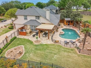 A residential backyard with a swimming pool, patio furniture, and a small wooden structure. - Stunning 6br, Pool - Great for Big Groups (Rowlett)