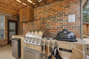 Cocina exterior con parrilla, horno empotrado y encimera de piedra.